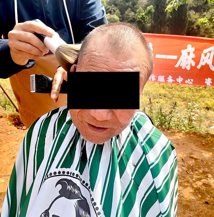 Image of victim of leprosy receiving a hair cut